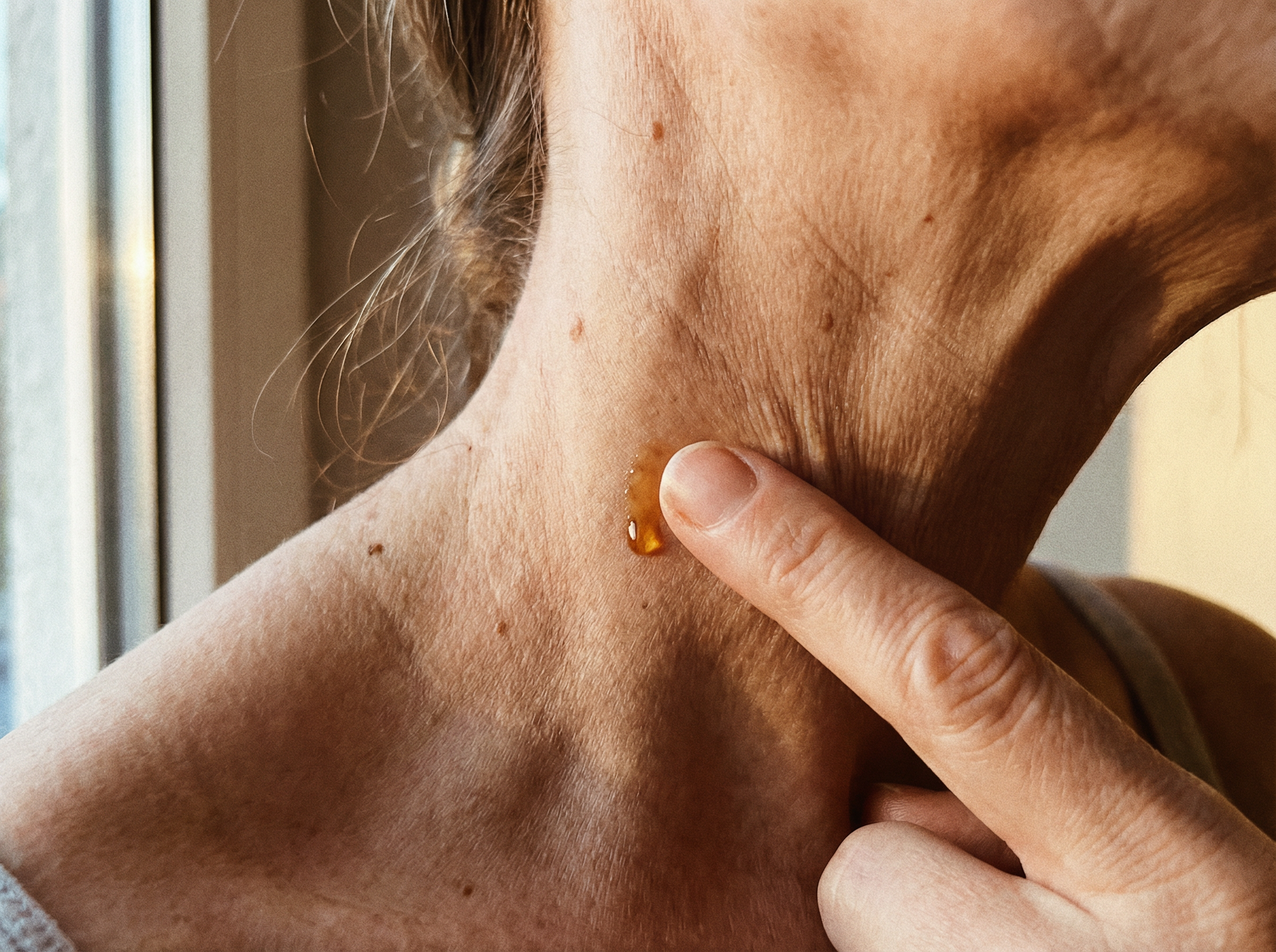 Close-up of essential oil being applied to pulse point on neck