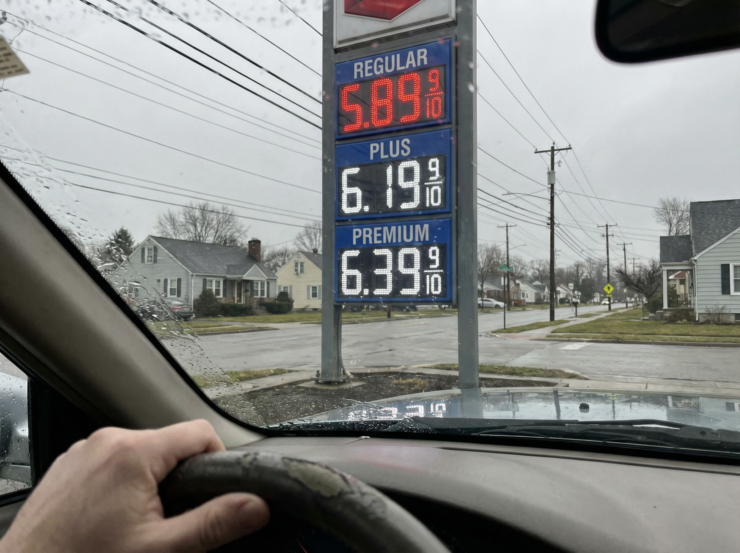 Gas station price sign showing high fuel prices through a car windshield, reflecting the economic pressure on American households